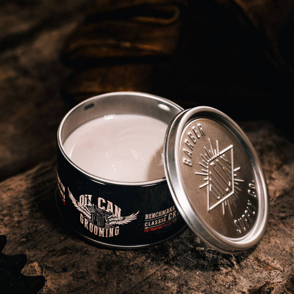 Oil Can Grooming's Benchmark Classic Hair Cream open tin on rustic wooden surface with vintage barbershop styling accessories