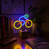 Colourful bicycle neon lamp on a desk beside books and plants with neon light reflections in a moody interior