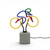 Multi coloured bicycle neon lamp on concrete effect base with visible power cable against white background