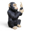 Black resin monkey ornament with raised middle finger on white background