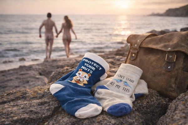 Funny novelty socks on rocky beach with coastal sunset background and leather bag lifestyle scene