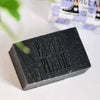 Paper Plane charcoal soap bar with embossed logo on light surface