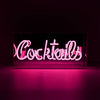 Pink Cocktails glass neon sign glowing inside a clear acrylic display box against a dark background