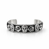 Sterling silver cuff bracelet with skull and flower design and oxidised finish on white background, front view