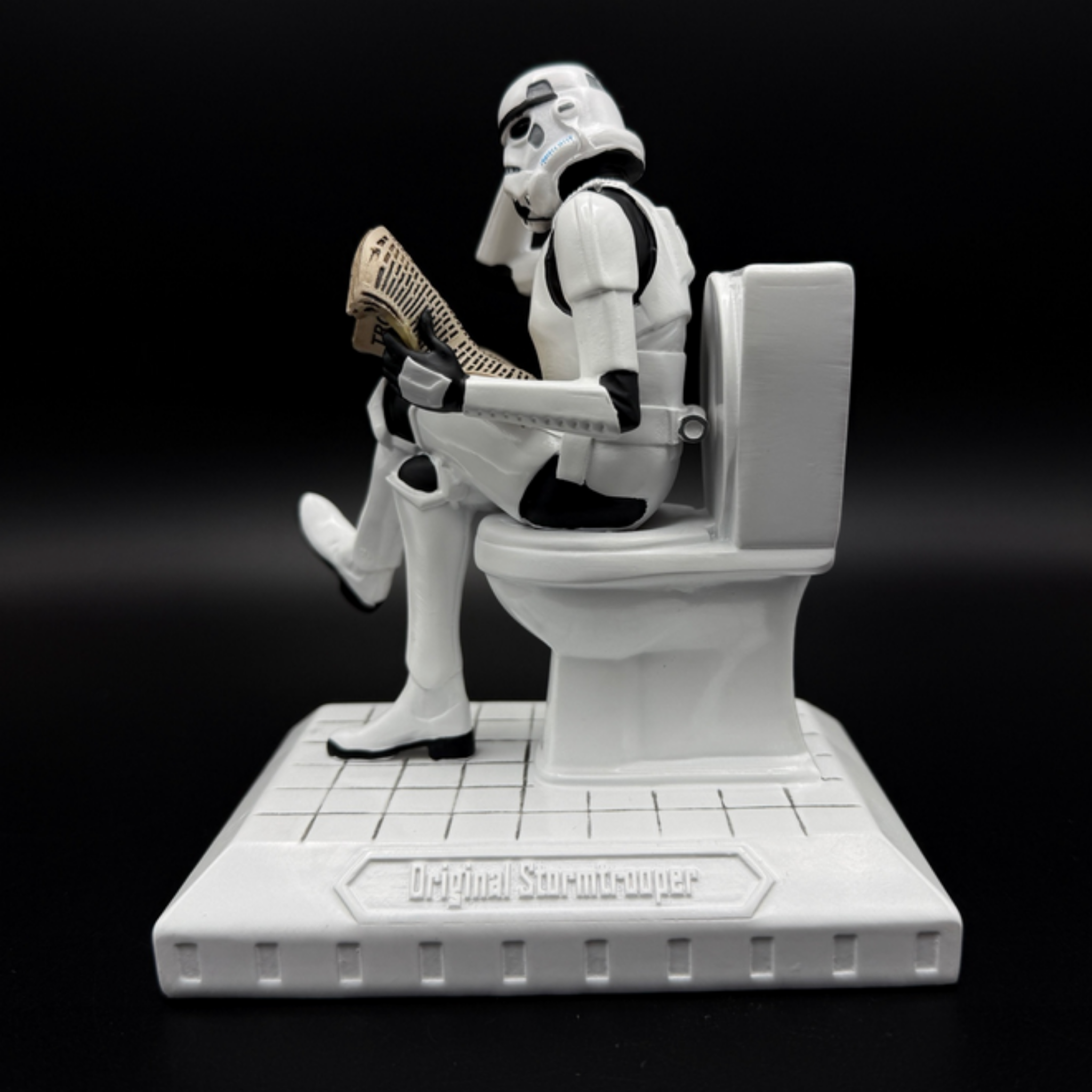 Officially licensed Stormtrooper Pooper Trooper figurine seated on a toilet reading a newspaper left side view