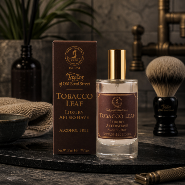 Taylor of Old Bond Street Tobacco Leaf aftershave in a luxury masculine grooming scene with shaving brush and dark stone textures