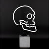 White skull neon lamp on concrete effect base against a dark background