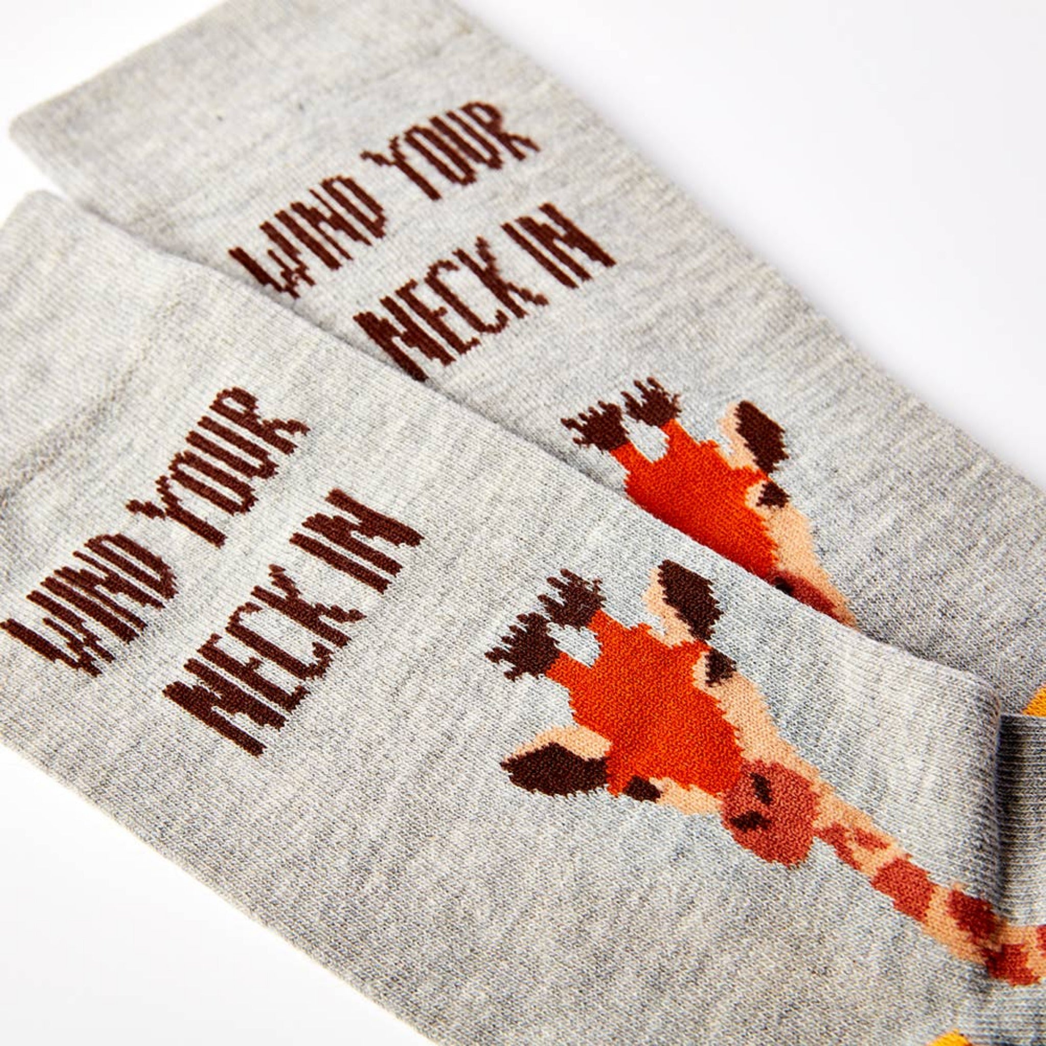 close up of Wind Your Neck In socks showing giraffe design and text